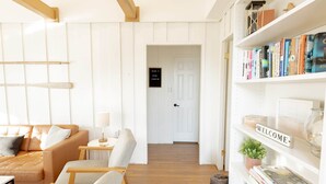 Un salon chaleureux avec un canapé, des fauteuils, une petite table et une bibliothèque remplie de livres.