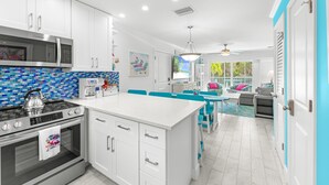 A modern kitchen with white cabinetry, a stainless steel stove, and a blue-tiled backsplash.