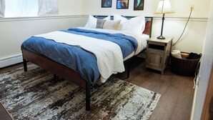 A bedroom with a bed, a nightstand, a lamp, a rug, and wall art.