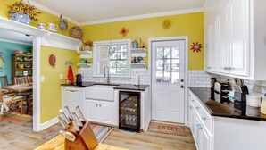 A kitchen with white cabinets, a refrigerator, and a dining area with a table and chairs.
