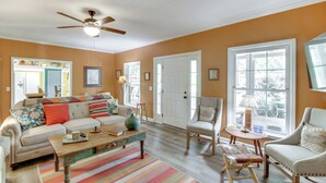 A living room with a sofa, armchairs, a coffee table, and a ceiling fan.