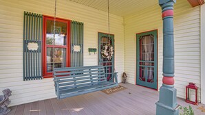 A porch with a hanging swing, a bench, and a statue. - Walk to Downtown: The Porch Swing Cottage (Winnsboro)