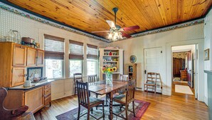 A dining area with wooden furniture, a ceiling fan, and a window with blinds. - Walk to Downtown: The Porch Swing Cottage (Winnsboro)