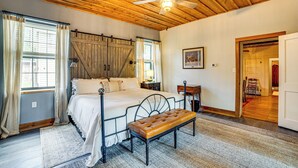 A bedroom with a bed, a bench, a ceiling fan, and a wooden ceiling. - Walk to Downtown: The Porch Swing Cottage (Winnsboro)