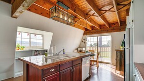A kitchen with wooden beams, a large island with a sink, and a view of the outdoors. - Mtn & Golf Course View: Oregon Outback Getaway! (Lakeview)