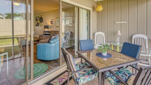 Un'ampia veranda con porta in vetro che conduce a un soggiorno, con un tavolo in vetro, sedie e una pianta in vaso.