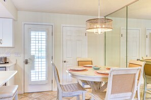A dining area with a round table, chairs, a chandelier, and a door with a window. - Relax Poolside & Walk to Beach! Resort PCB Retreat (Panama City Beach)