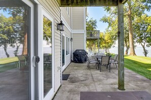 A covered patio with a table and chairs, a grill, and a view of a lake. - Marina Access & Lake Views: Family Gem in Onamia (Onamia)