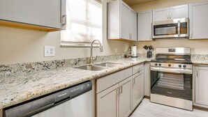 Cozinha moderna com bancadas de granito, eletrodomésticos de aço inoxidável e armários em tons claros.