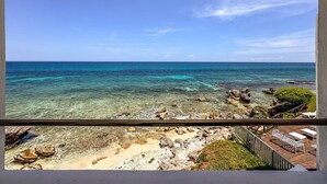 En tydlig vy över en strand med klippformationer och ett lugnt hav.