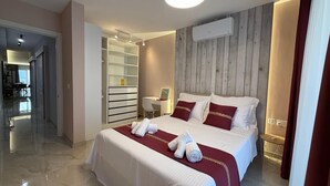 A hotel room with a bed, a desk, a chair, a wardrobe, and an air conditioning unit. - White Lotus 10 of 10 (St. Paul's Bay)