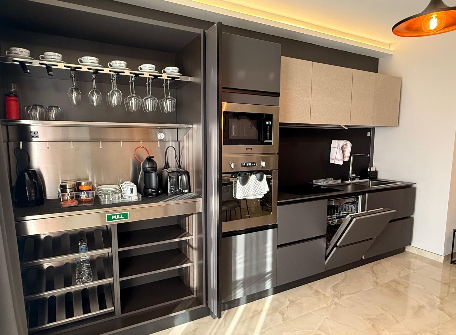 A modern kitchen with stainless steel appliances, a pull-out pantry, and a hanging wine rack.