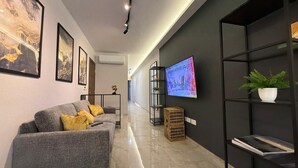A modern living room with a grey sofa, a flat-screen TV, and a black bookshelf. - White Lotus 10 of 10 (St. Paul's Bay)