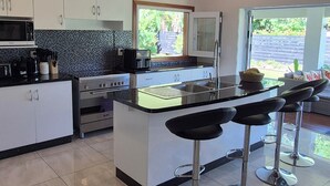 Une cuisine moderne dotée d’un îlot central, de tabourets de bar, d’un ventilateur de plafond et offrant une vue sur l’extérieur.