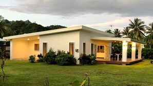 Une maison moderne à deux étages, dotée d’un toit plat, de grandes fenêtres et d’un espace extérieur aménagé avec un coin salon couvert.