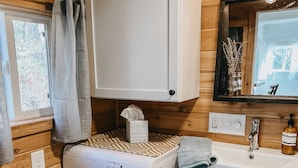 A compact laundry area with a washing machine, a sink, and a cabinet.