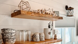 A kitchen with wooden shelves holding various kitchenware, a toaster, and a coffee maker.