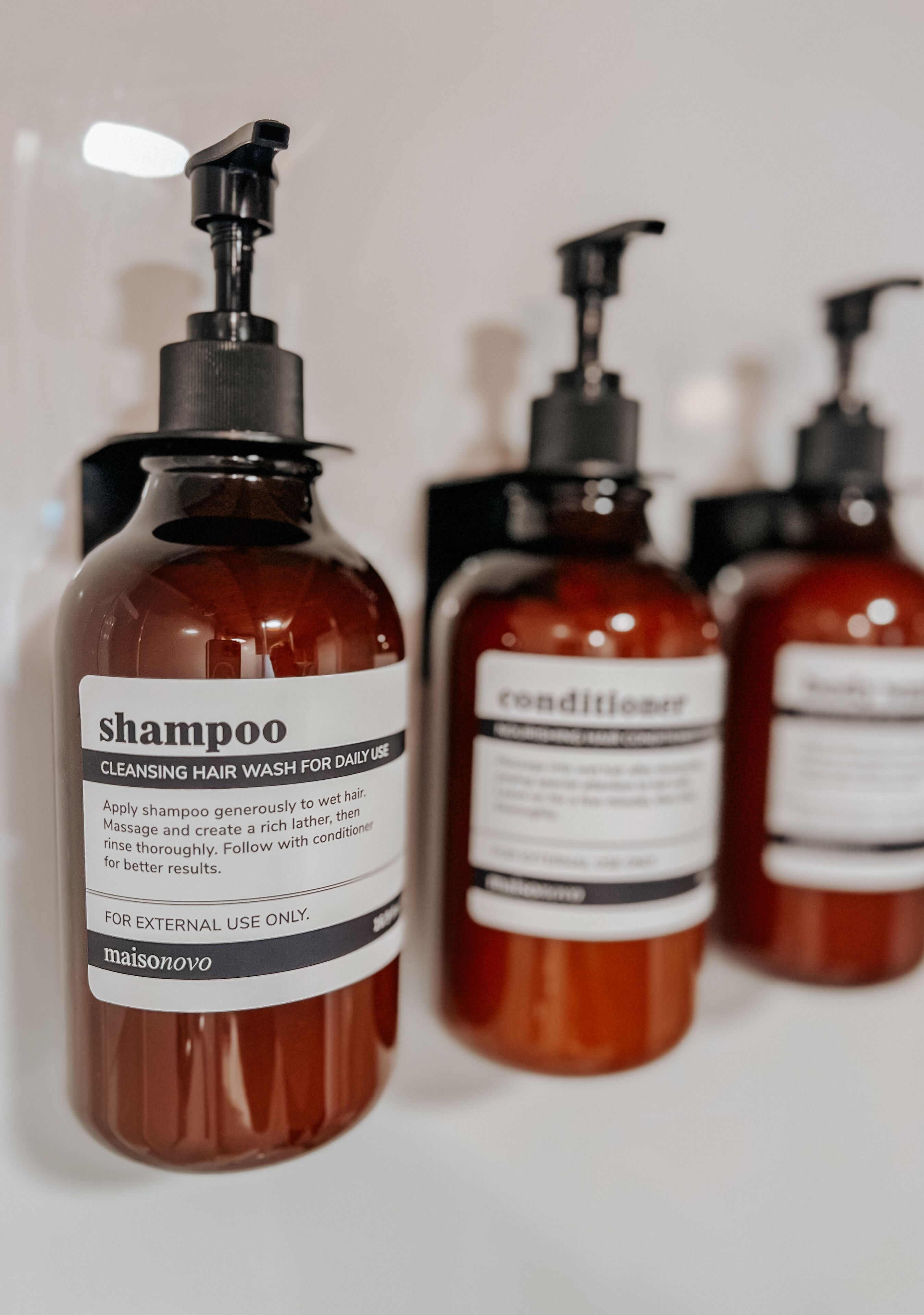 Fire flasker hårprodukter med pumper, mærket shampoo og balsam.