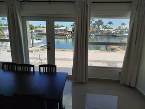 A room with a large window overlooking a marina and beach. There is a dining table with chairs. - Sensational 2br/2bth Water View #1 (Treasure Island)