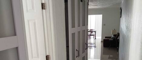A hallway with a white door, a sliding barn door, and a view into another room with a desk and chair.