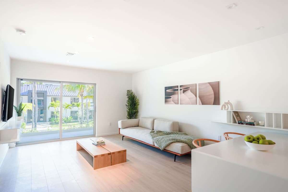 Una sala de estar moderna con sofá, mesa de centro y vistas a un balcón con plantas.