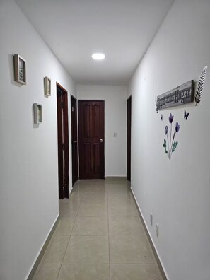 Un pasillo con una puerta de madera, un cartel que dice 'Hogar y Hogar' y un adorno floral en la pared.