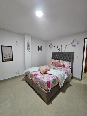 Un dormitorio con una cama, una mesita de noche y un estante en la pared.