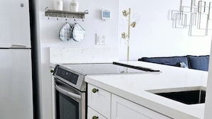 A modern kitchen with white cabinetry, a stainless steel oven, and a built-in dishwasher. - Palm Desert Studio at Shadow Mountain Resort...steps to El Paseo`s Charms (Palm Desert)