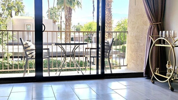 A spacious balcony with a view of palm trees and a building in the background. - Palm Desert Studio at Shadow Mountain Resort...steps to El Paseo`s Charms (Palm Desert)