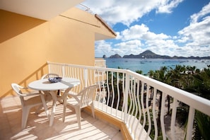 A balcony with a table and chairs, overlooking a coastal view with boats and palm trees. - Deluxe Condo at Villa Del Palmar (Cabo San Lucas)