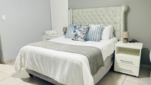 Une chambre bien rangée, avec un grand lit, une table de chevet avec une lampe et une armoire.