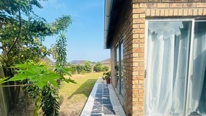 Une maison avec un chemin pavé menant à une porte en verre, entourée de verdure et sous un ciel dégagé.