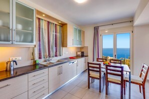 Una cocina moderna con vista al mar, que incluye un comedor con mesa y sillas.