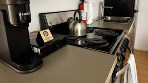 Eine Küchenzeile mit einer Keurig-Kaffeemaschine, einem Wasserkocher, einem Herd und einem Feuerlöscher.