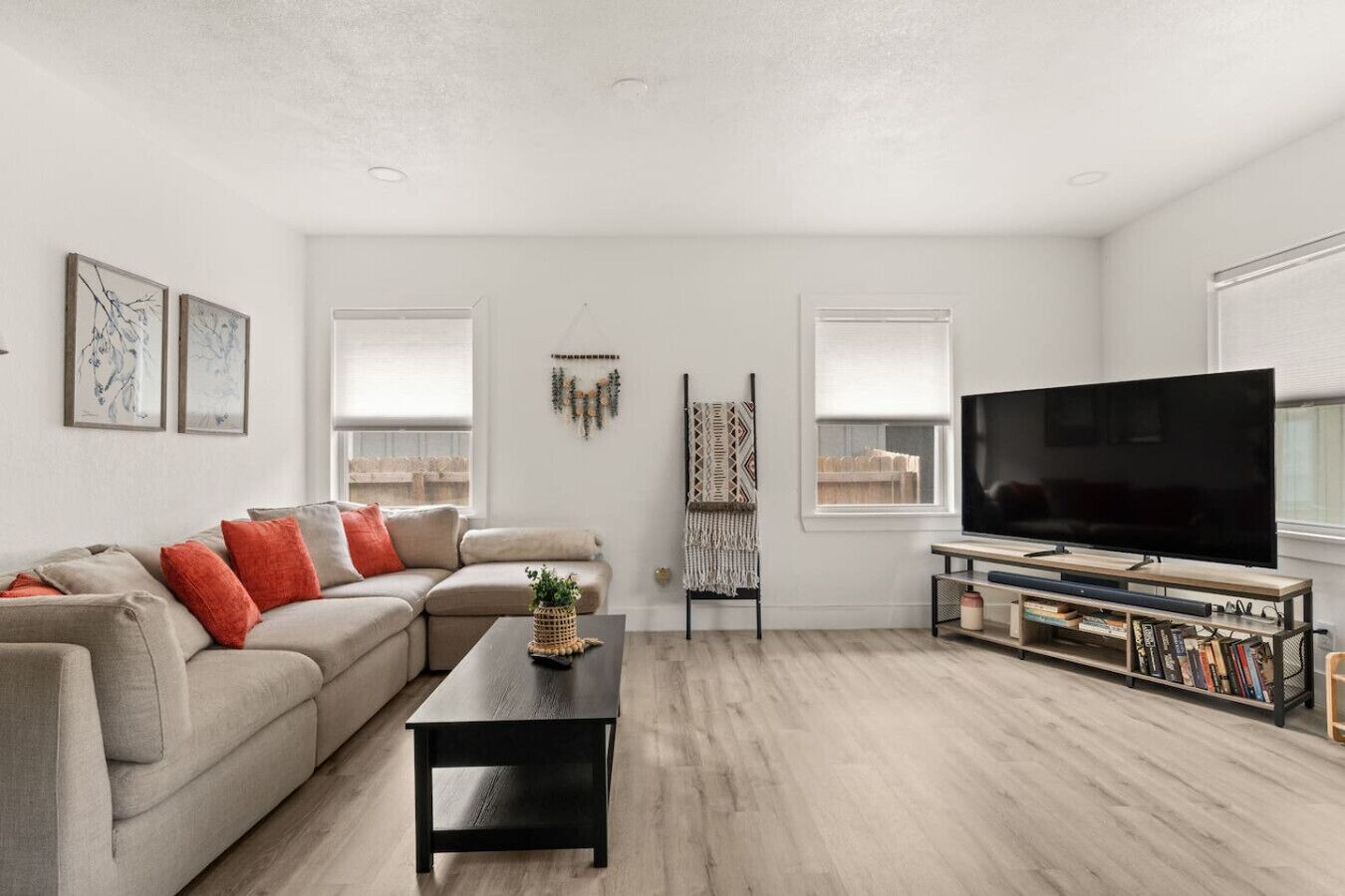 A modern living room with a sectional sofa, a coffee table, a TV, and a bookshelf.