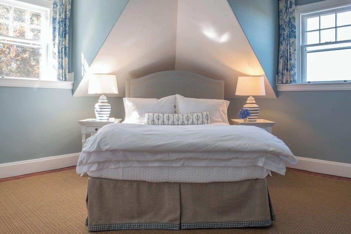 A bedroom with a bed, two bedside tables, and a window with curtains.