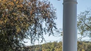 A gazebo with a white railing overlooking a lake with boats and trees in the background. - Margin Street Inn (Westerly)