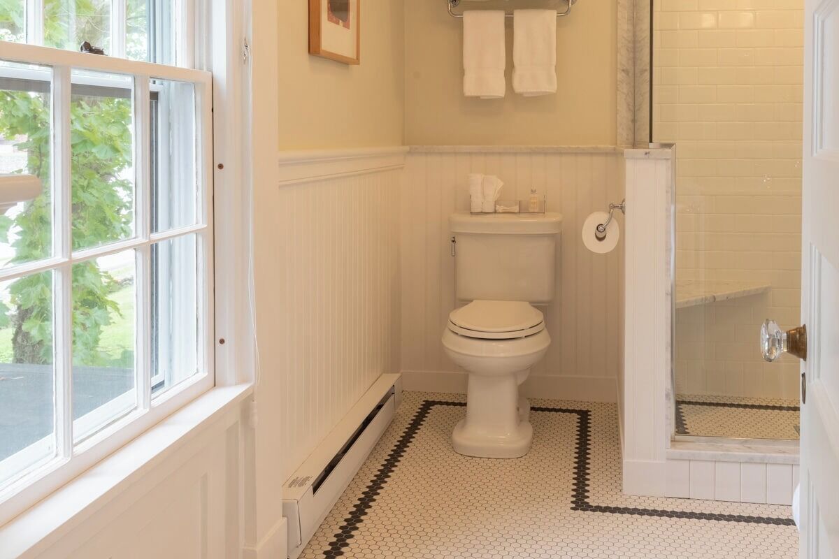 A bathroom with a toilet, a shower, and a window.
