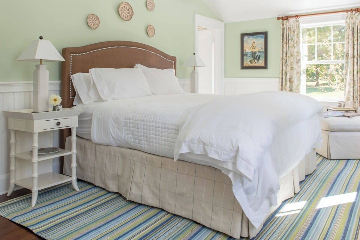 A neatly arranged bedroom with a bed, bedside tables, and a window with curtains.