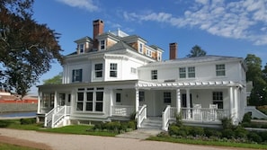 A two-story white house with a porch, a covered front porch, and a small staircase leading to the entrance.