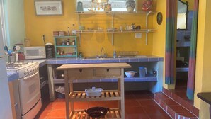 A compact kitchen with a stove, microwave, and shelves above the sink.