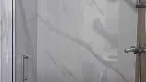 Une douche entièrementClose avec des parois en verre, un mur en marbre et un plancher en bois.
