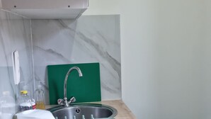 Une cuisine au design moderne, dotée d’une cuisinière intégrée, d’un évier et d’une planche à découper verte.