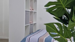 Une chambre moderne avec un lit, une armoire blanche et une plante en pot.