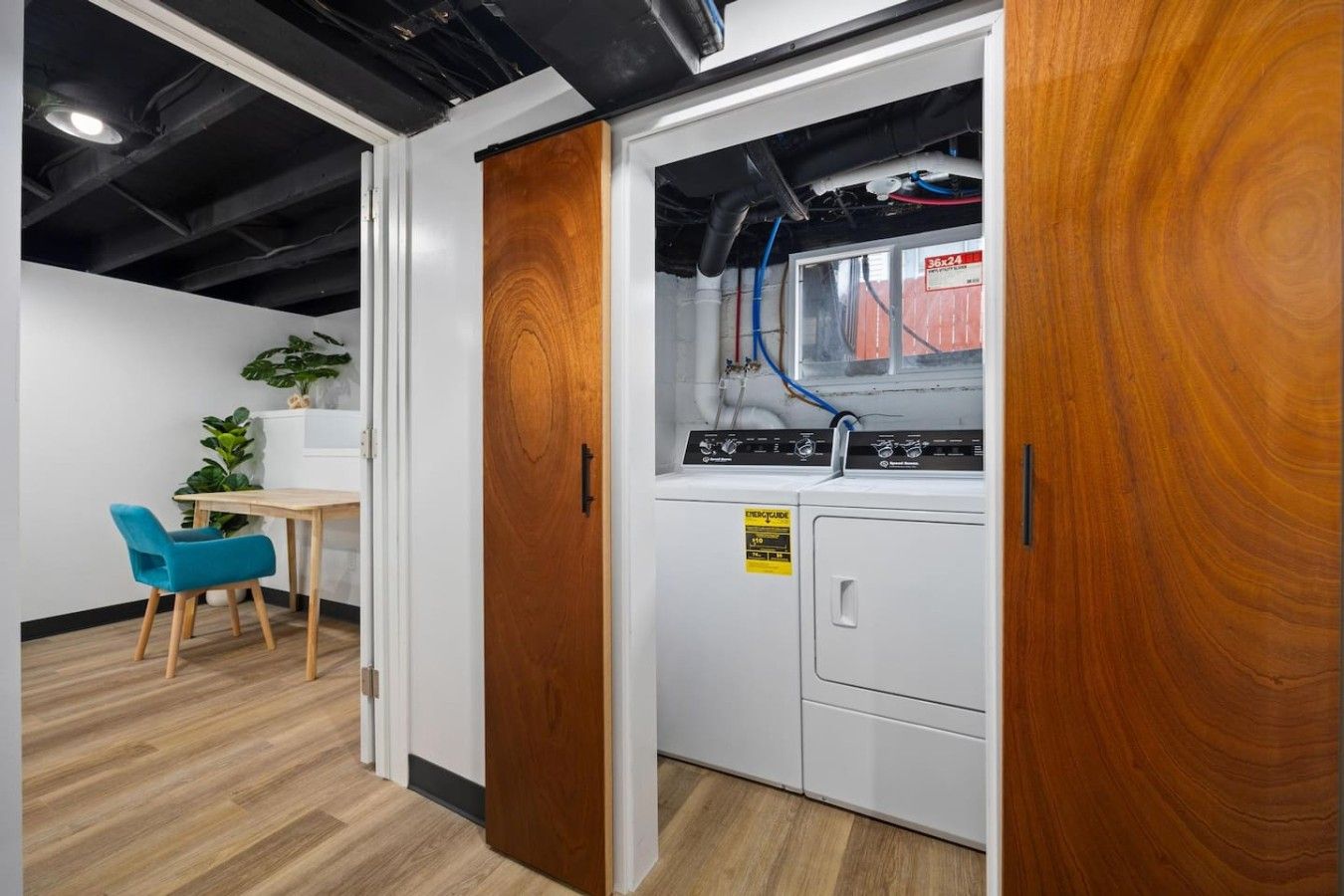 A laundry room with a washing machine, a sink, and a wooden door.