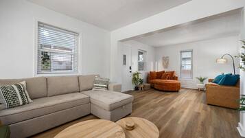 A modern living room with a sectional sofa, a round wooden coffee table, and a curved orange sofa.