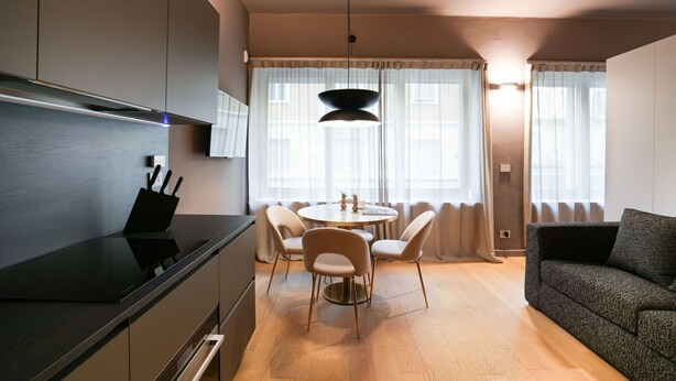 Eine moderne Küche mit Essbereich, einer Couch und einer Pendelleuchte.