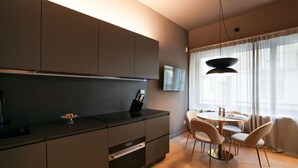 Eine moderne Küche mit dunklen Schränken, einer schwarzen Arbeitsplatte und einem Essbereich mit rundem Tisch und Stühlen.