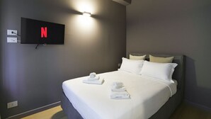 Ein Hotelzimmer mit Bett, Flachbildfernseher an der Wand und Steckdose.