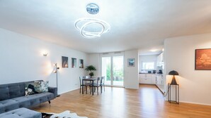 A modern living room with a grey sofa, a cowhide rug, and a dining area with a table and chairs. - EXQUIS 2BR Artistic Apartment TAO I Garden I Panzer Kaserne I Parking I Familly (Holzgerlingen)